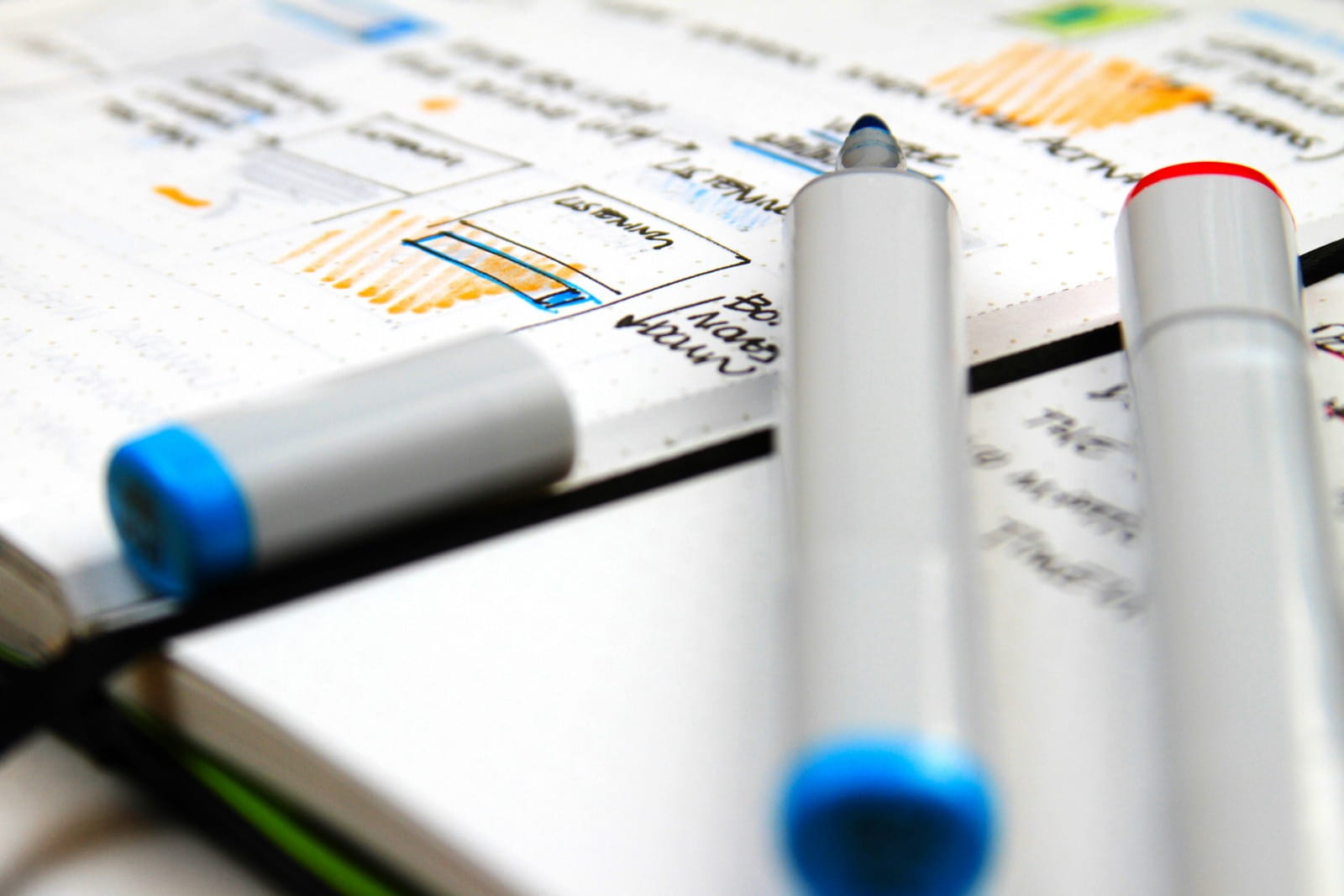 Design marker pens resting on a notebook of hand-drawn interface wireframe sketches