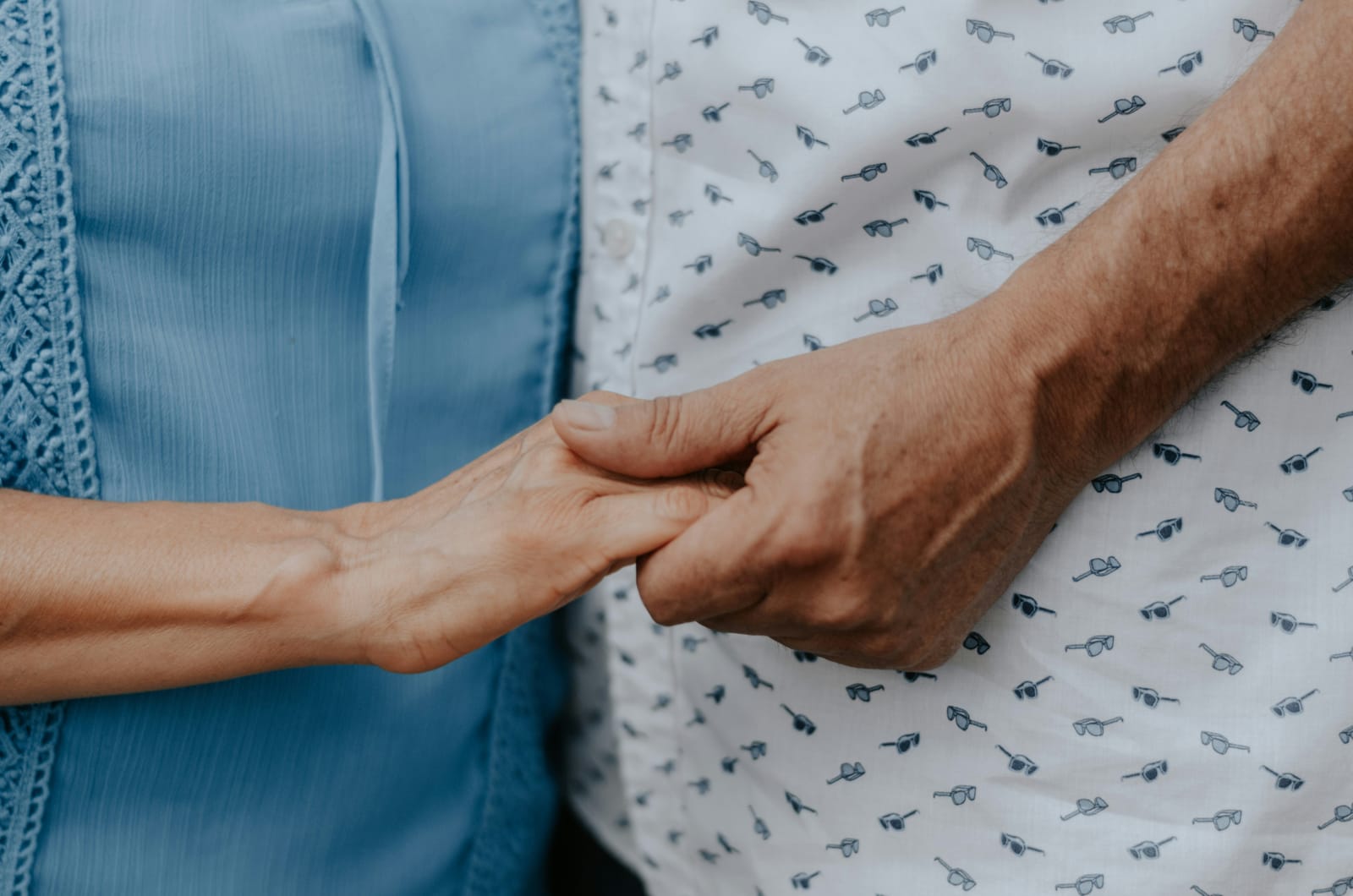 Two people holding hands, one older, in a moment of care