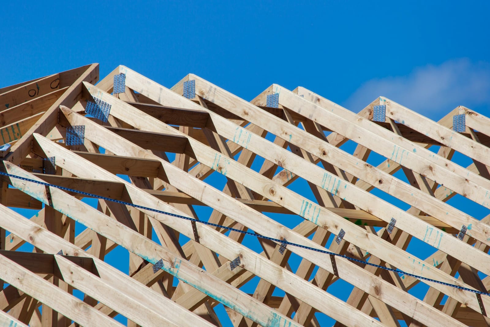 Timber roof trusses with steel bracing against a blue sky