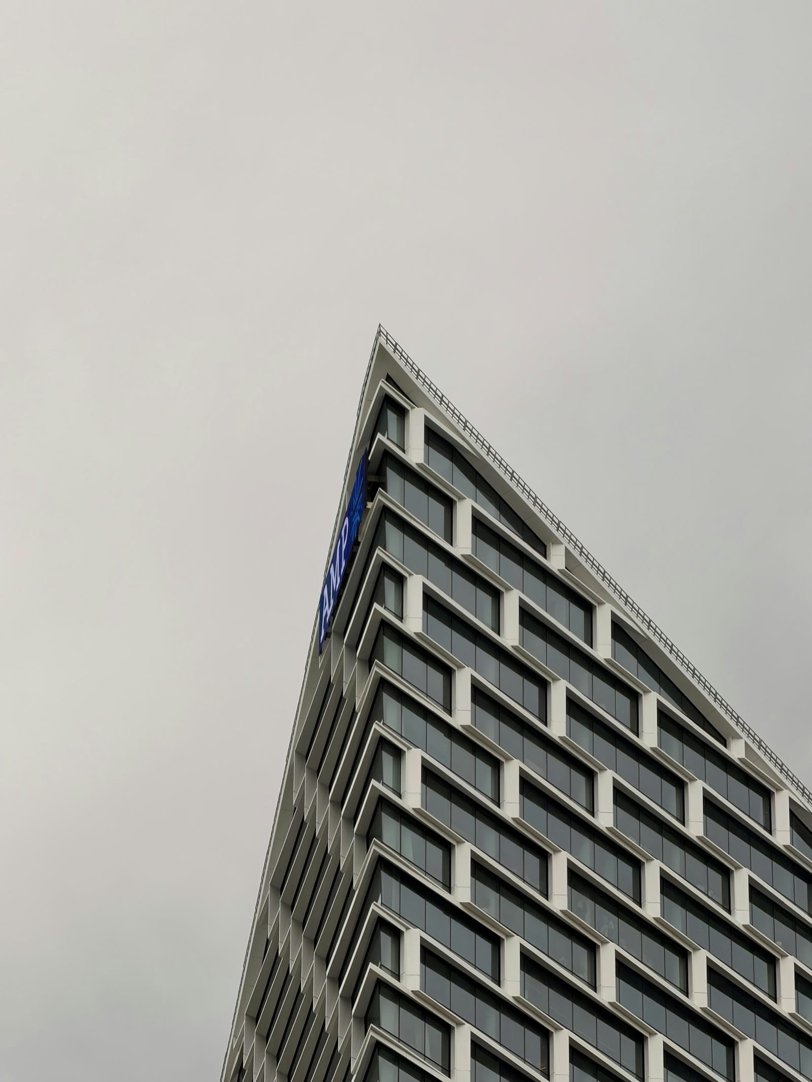 Looking up at the corner of a city office tower against an overcast sky