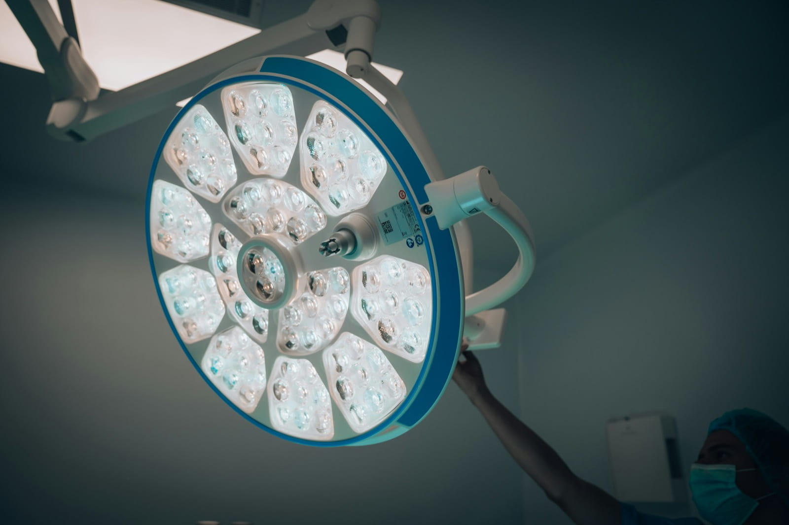 A surgeon in scrubs adjusting a large LED operating theatre light