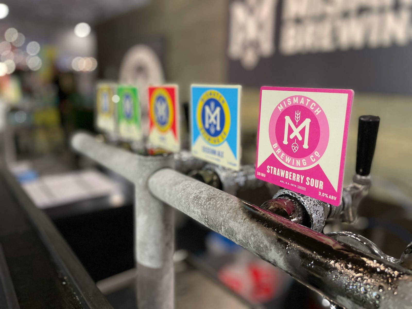 Row of craft beer taps with colourful branded badges at a bar