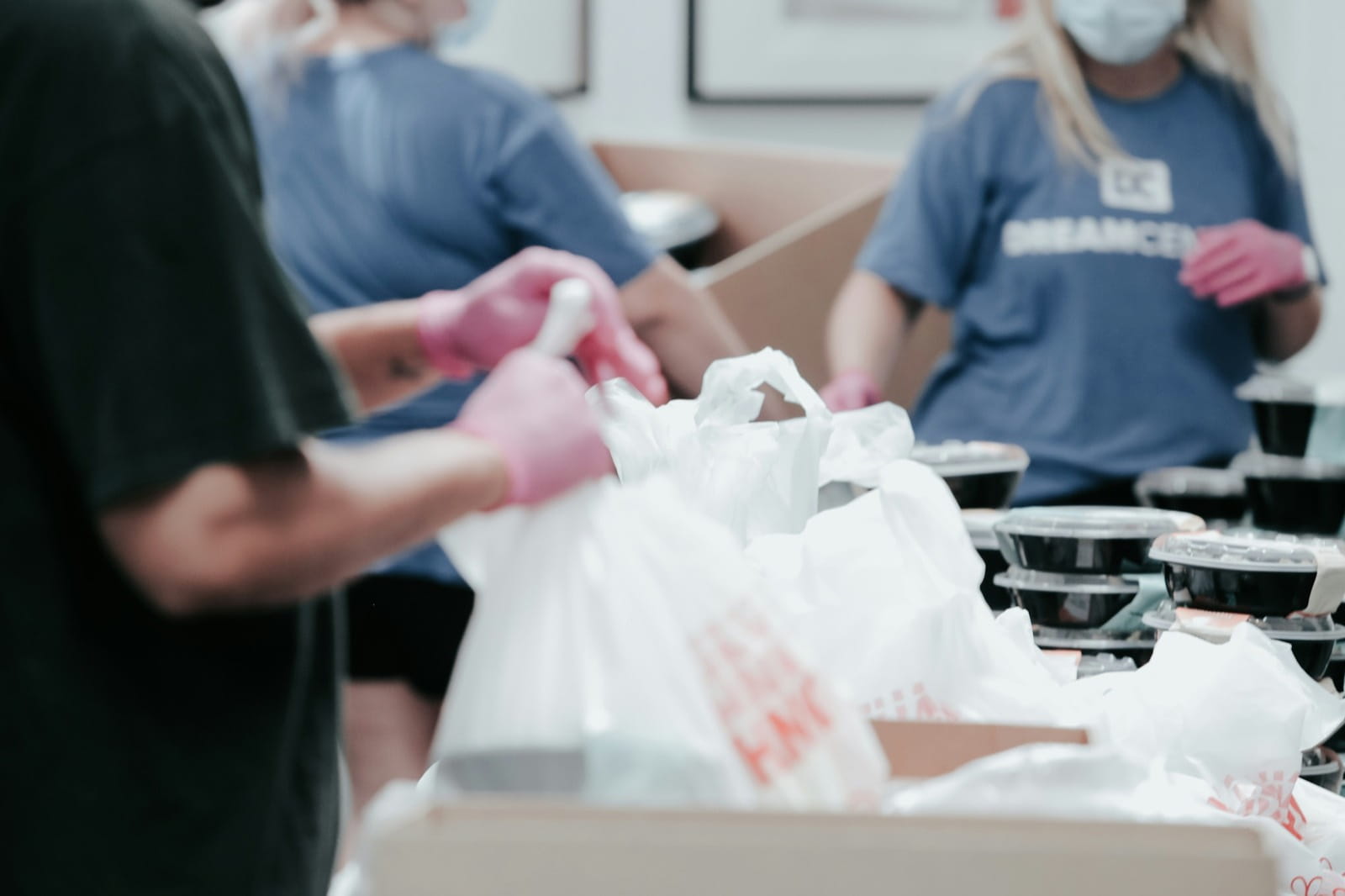 Volunteers in gloves packing meals into bags at a charity food drive